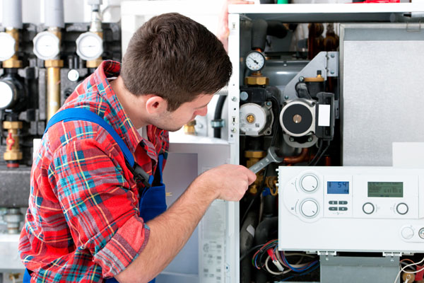 HVAC technician inspecting and repairing boiler controls in Saratoga Springs