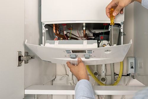 HVAC technician repairing an indoor boiler in Saratoga Springs